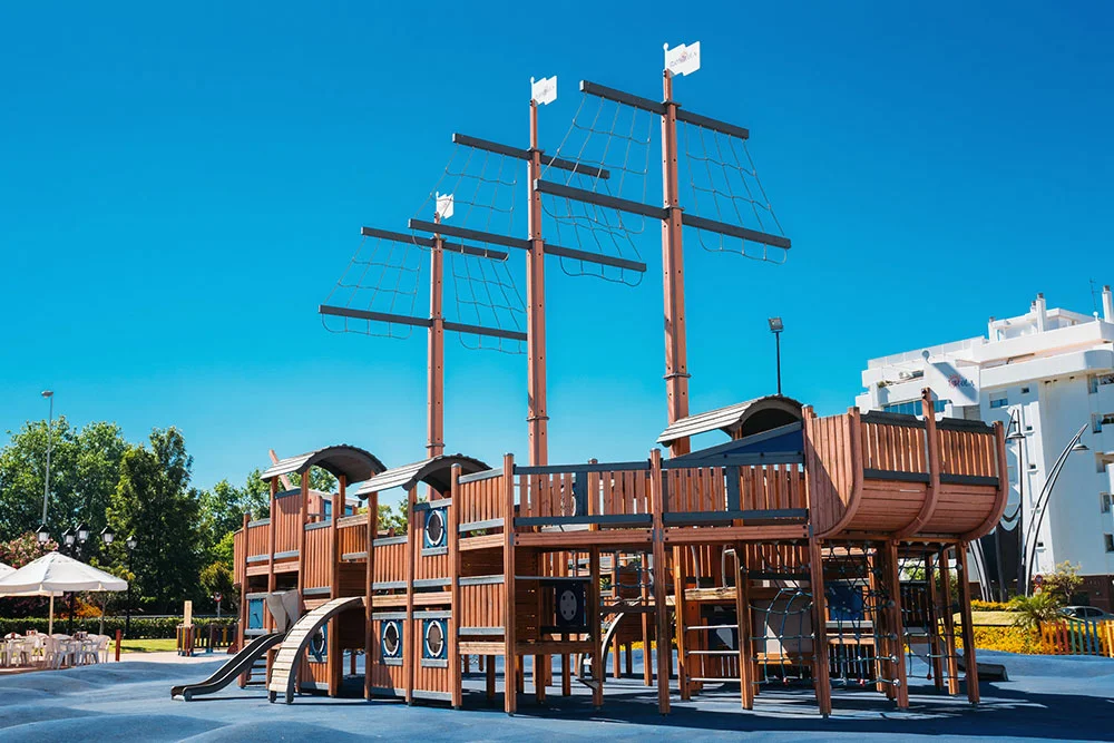 A large, wooden pirate ship playground structure. Themed playground concept.